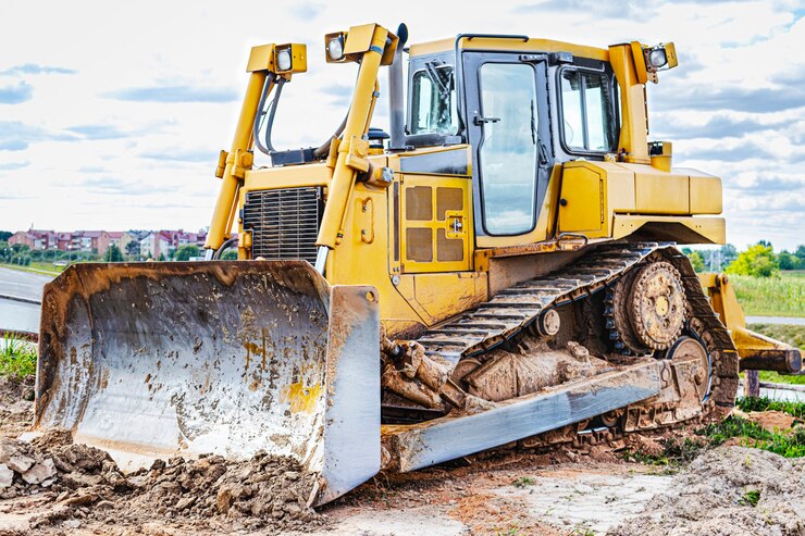 Photo la machine de bulldozer nivelle le chantier de construction. le génie civil avec le tracteur déplace la terre. fermer. machinerie lourde de construction.