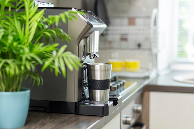 Machine à café électrique moderne avec tasse sur le comptoir de la cuisine