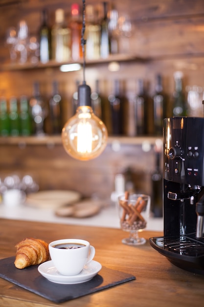 Machine à café moderne à côté d'une tasse de café esoresso sur un comptoir en bois. Café d'époque. Café savoureux.