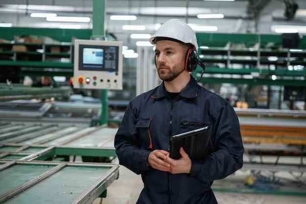 La machine derrière le bloc-notes de l'ouvrier de l'usine est à l'intérieur avec un casque