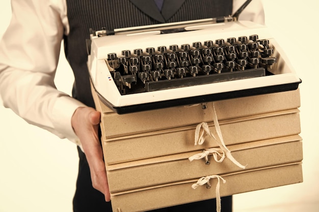 Machine à écrire rétro et tas de dossiers dans les mains des hommes travaillent