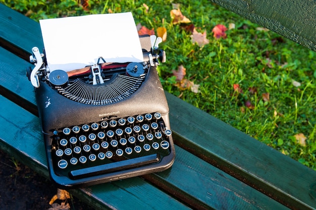 Machine à écrire vintage antique sur fond d'automne avec des feuilles tombées sur le banc