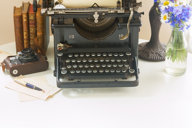 Machine à écrire vintage noire avec des livres sur une table en bois blanche