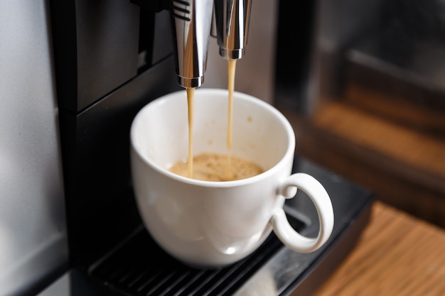 Photo machine à expresso versant du café dans une tasse blanche