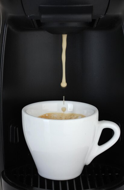 Une machine à expresso versant du café dans une tasse blanche.