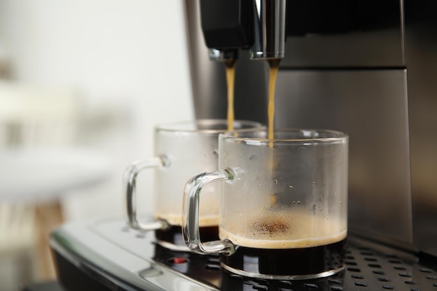 Machine à expresso versant du café dans des tasses en verre sur fond flou gros plan Espace pour le texte