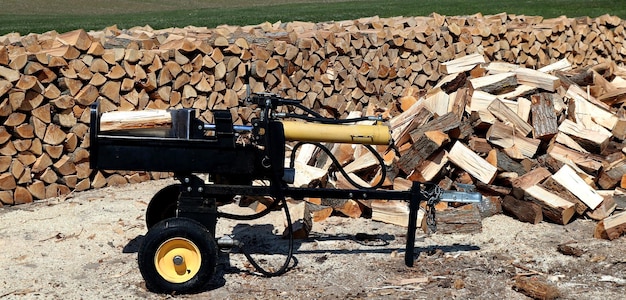 Photo machine à fendre le bois avec des bûches empilées en fond de pile