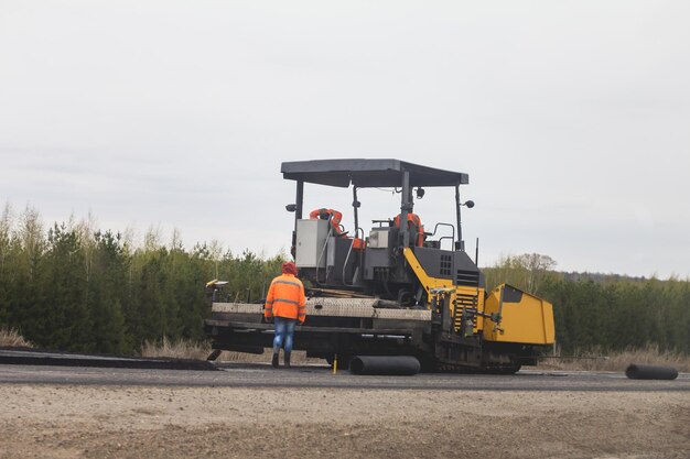 Machine de finisseur d'asphalte à l'autoroute avec des travailleurs - construction de routes, téléobjectif