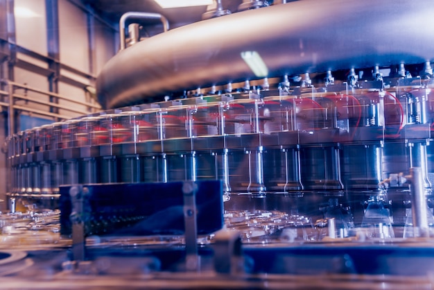La machine de remplissage automatique verse de l'eau dans des bouteilles en plastique PET. Production brassicole.