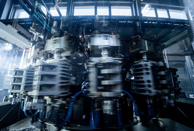 La machine de remplissage automatique verse de l'eau dans des bouteilles en plastique pour animaux de compagnie dans une usine de boissons moderne