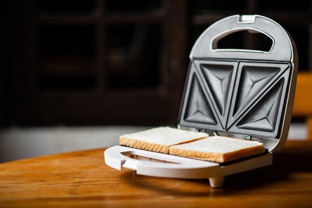 Machine à sandwich avec toast préparé sur table en bois sur fond sombre Place pour le texte