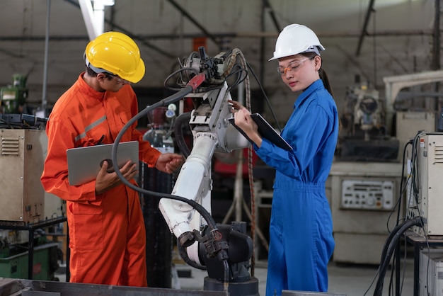 Machine de soudage à bras robotisé de contrôle d'inspection d'ingénieurs masculins et féminins avec un ordinateur portable en usine