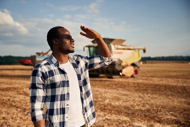 Photo la machinerie derrière le beau afro-américain est dans le domaine de l'agriculture