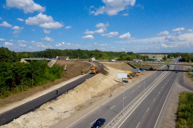 Machinerie lourde sur un chantier de construction contre le ciel bleu. Vue aérienne. Matériaux pour les producteurs d'asphalte et de pavage de route, construction.