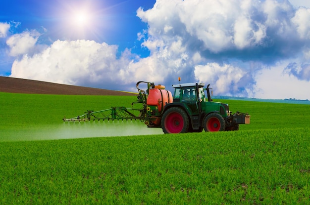Machines agricoles pulvérisant un insecticide sur le champ vert fond de printemps saisonnier naturel agricole
