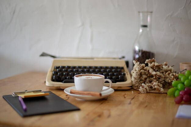 Des machines à écrire vintage et une tasse de café sur une table en bois.