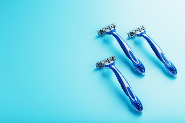 Machines à raser bleues d'affilée sur fond bleu avec des glaçons