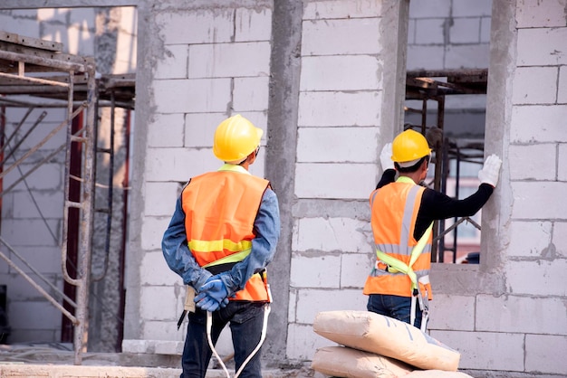 Le maçon de brique léger est fait d'argile expansée Éléments de construction en maçonnerie Le constructeur tient les briques Un homme portant un casque sur un chantier de construction