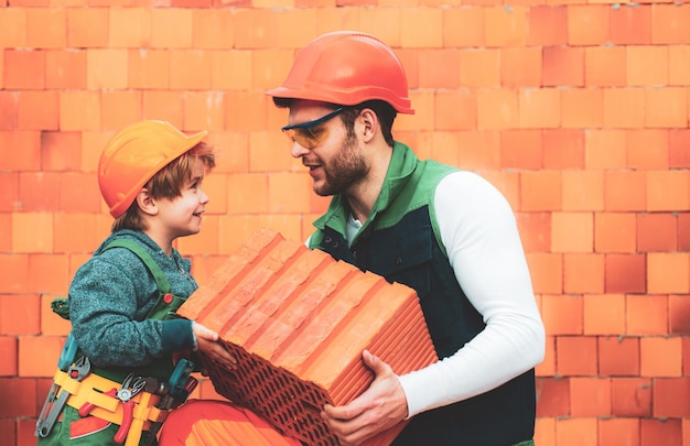 Le maçon fait de la maçonnerie, le constructeur travaille avec une couche de briques. Frères au travail. Petit enfant garçon réparant en atelier.