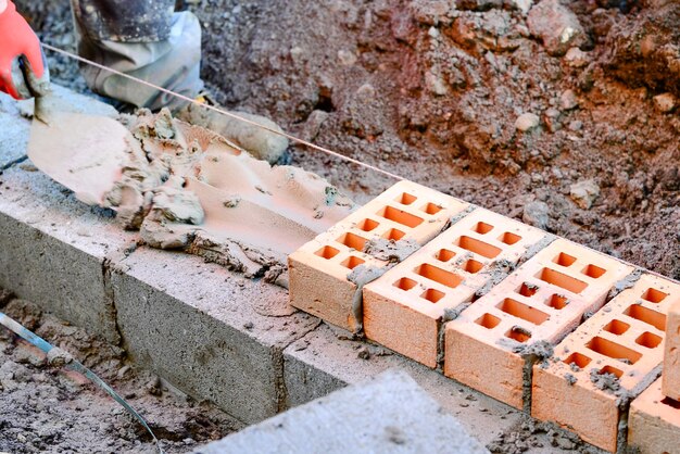 Photo maçon pose des briques sur chantier