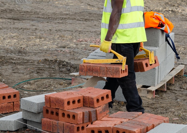 Photo maçons apportant des briques près de son lieu de travail à l'aide de lève-briques