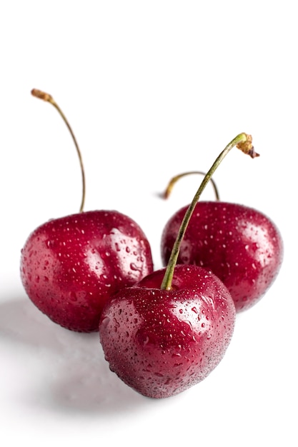 Macro de baies de cerises rouges avec des gouttes d'eau sur fond blanc