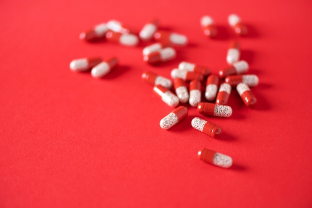 Macro de capsules rouges sur fond rouge. Copiez l'espace. Bande de médicaments, traitement contre la grippe froide.