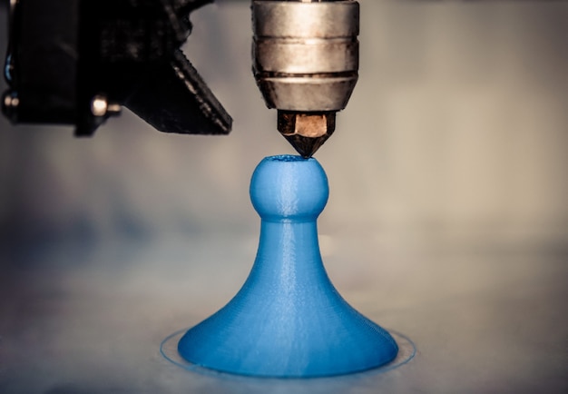 Macro de gros plan de la figure d'impression d'une imprimante 3D moderne. L'imprimante 3d tridimensionnelle automatique effectue la modélisation des couleurs bleues en plastique en laboratoire. Traitement d'impression 3D avec fond blanc