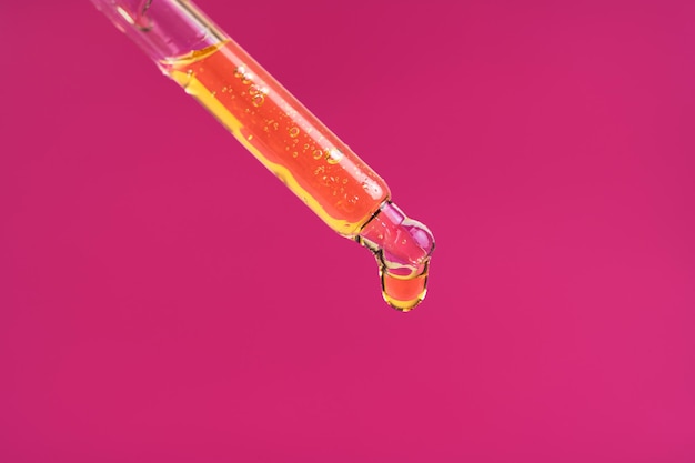 Macro photo de sérum cosmétique ou d'huile essentielle tombant du compte-gouttes en verre