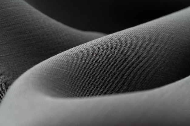 Macro photographie de la texture du tissu gris soie Luxueux fond de couture sombre Beau tissu satin brillant closeup copie espace Minimalisme abstrait monochrome