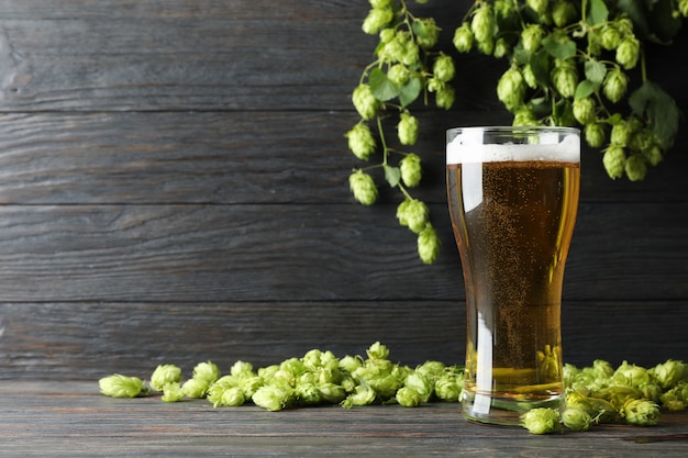 Mag avec de la bière, des épillets et du houblon sur une table en bois