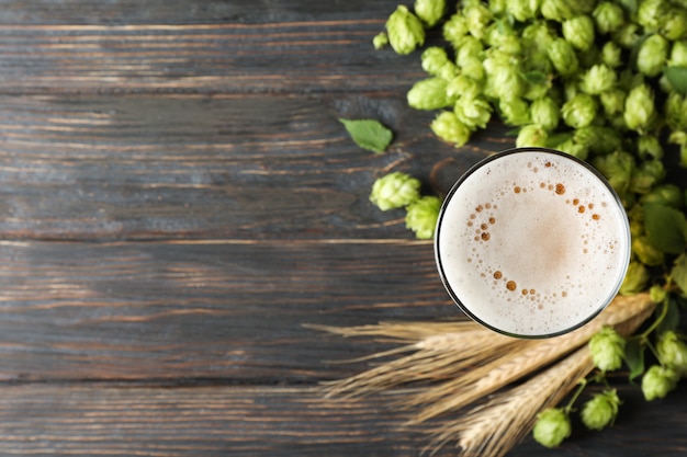 Mag avec de la bière, des épillets et du houblon sur une table en bois