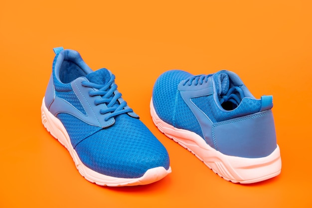 Magasin de chaussures. notion d'achat. chaussures pour l'entraînement. chaussures de sport pour la course. paire de chaussures de sport confortables. baskets bleues sportives. chaussures sur fond orange.