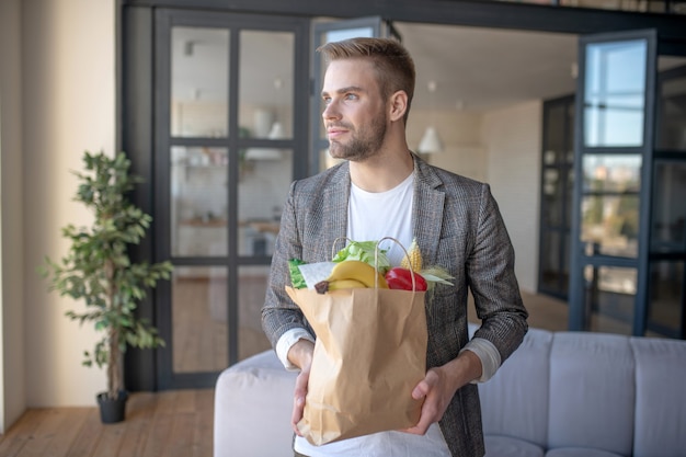 Magasin Grossery. Un homme tenant un paquet de légumes frais