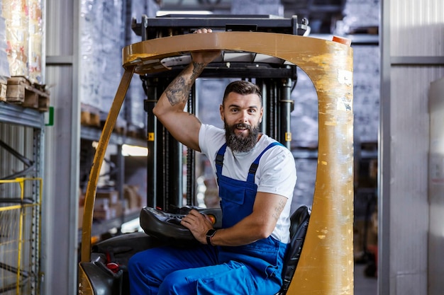 Photo le magasinier enthousiaste sourit et conduit un chariot élévateur