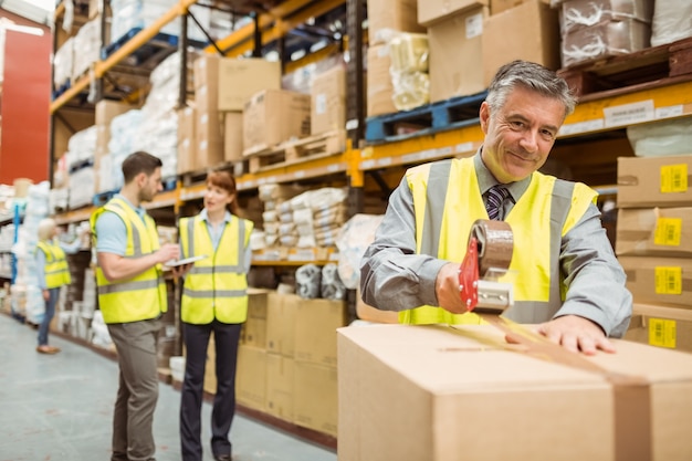 Magasinier scellant des boîtes en carton pour l&#39;expédition