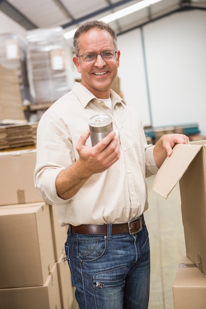 Magasinier souriant tenant une boîte de conserve en métal