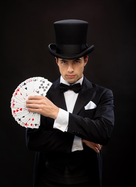 magie, performance, cirque, jeux d'argent, casino, poker, concept de spectacle - magicien en chapeau haut de forme montrant un tour avec des cartes à jouer