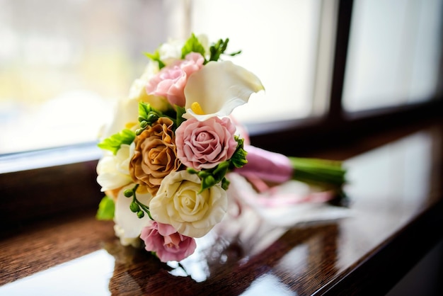 Magnifique bouquet de mariage tendre avec crème ivoire et roses roses sur un rebord de fenêtre Gros plan