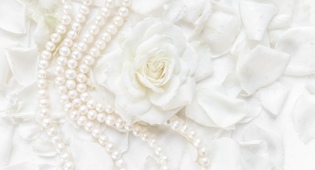Magnifique collier de rose blanche et de perles sur fond de pétales Idéal pour carte de voeux
