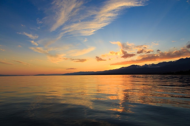 Magnifique coucher de soleil nuageux sur la mer et les montagnes Ciel lumineux dans les rayons du soleil orange naturel