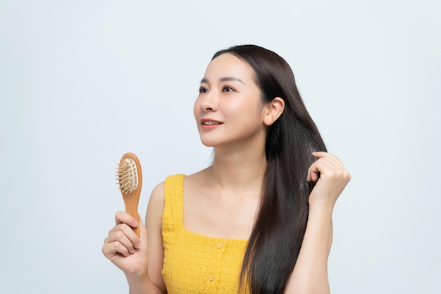 Une magnifique femme asiatique se brosse les cheveux en bonne santé.