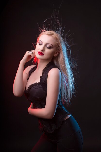 Magnifique femme blonde en corset et lumière rouge au studio