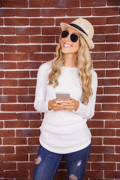 Magnifique hipster blonde souriante tenant le smartphone