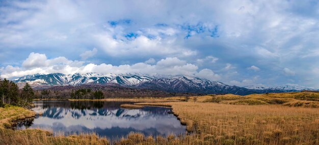 Magnifique lac reflétant le ciel bleu comme un miroir d'une chaîne de montagnes vallonnées et d'une forêt