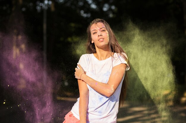 Magnifique mannequin asiatique bronzée vêtue d'une chemise blanche, jouant avec de la peinture Holi verte et violette