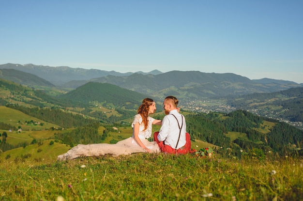 magnifique mariée et marié élégant assis sur le dessus couple de mariage boho à la vue imprenable sur les montagnes