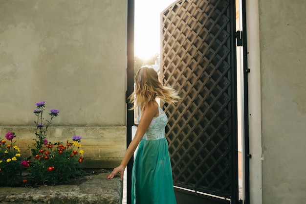 Magnifique modèle blonde aux cheveux ondulés en mouvement, posant sous les rayons du soleil le matin