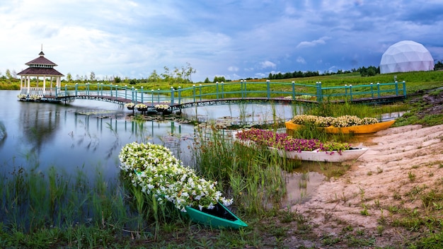 Magnifique paysage d'été et lieu de méditation. Un belvédère en bois, une plate-forme et plusieurs petits bateaux remplis de fleurs au bord du lac.