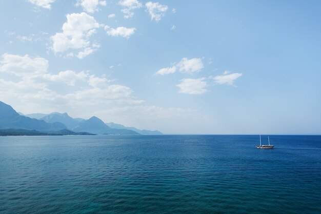 Magnifique paysage marin avec mer, nuages, montagnes et yacht